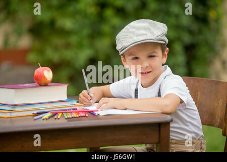 Il ragazzo, scrivere i suoi compiti a casa da scuola, il disegno e la scrittura nel suo notebook, imparare cose nuove, all'aperto Foto Stock