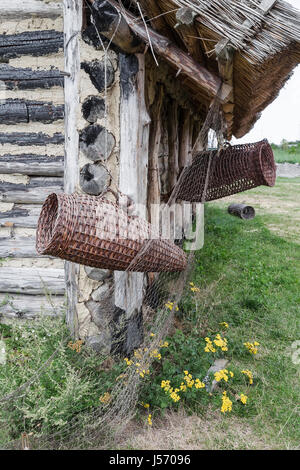 Rete da pesca e accessori per la pesca appesa al muro di una capanna in legno Foto Stock