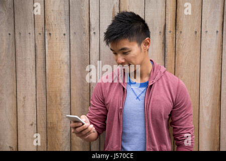 Uomo cinese in piedi in strada di città utilizzando il suo Smart Phone. Foto Stock