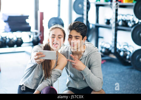 Montare il giovane nella moderna palestra crossfit con lo smartphone. Foto Stock