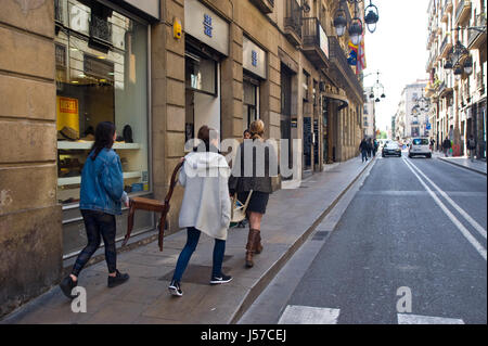 Le donne che trasportano sedie passato a piedi i negozi sulla strada di Barcellona Spagna ES UE Foto Stock