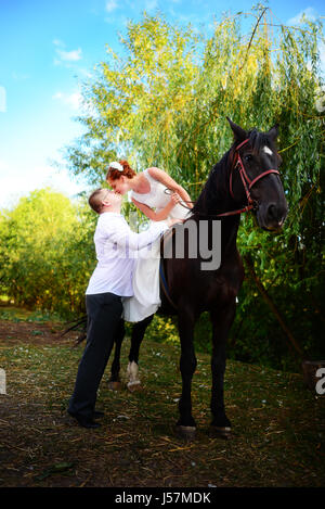 Lo sposo conduce il cavallo per la briglia. Sposa siede in sella a cavallo. Paese wedding Foto Stock