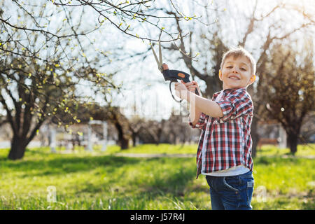 Adorable boy holding secateurs e sorridente Foto Stock