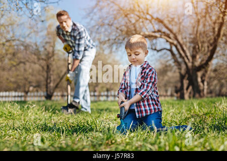Little Boy aiutando il padre in giardino Foto Stock