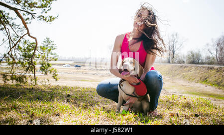 I giovani animali di razze di cani beagle passeggiate nel parco all'aperto. La ragazza cammina con cautela il cucciolo al guinzaglio, gioca e treni con lui Foto Stock