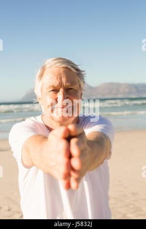 Ritratto di active senior uomo a praticare yoga in spiaggia Foto Stock