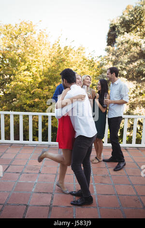Giovane che abbraccia ogni altra in balcone a casa Foto Stock