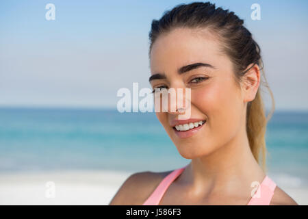 Ritratto di sorridere pretty woman in spiaggia contro sky Foto Stock