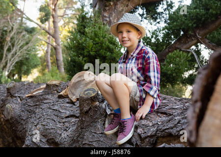 Ritratto di sorridere ragazzo seduto su i caduti tronco di albero Foto Stock