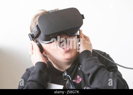 Una donna reagisce mentre indossa una realtà virtuale auricolare. Foto Stock