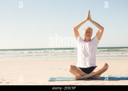 Lunghezza completa di senior uomo con gli occhi chiusi meditando a beach Foto Stock