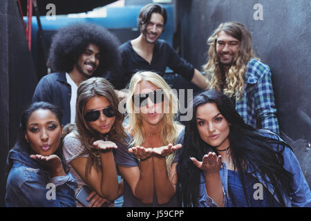 Donne bacio di soffiaggio con amici maschi in background in discoteca Foto Stock