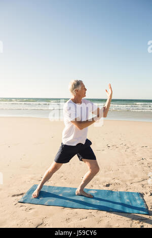 Lunghezza completa di active senior uomo a praticare yoga in spiaggia Foto Stock