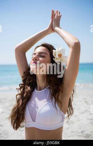 Close up di donna con gli occhi chiusi gli esercizi in spiaggia sulla giornata di sole Foto Stock