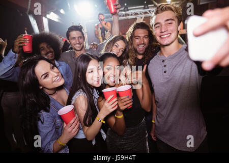 Happy amici prendendo selfie al popolare concerto di musica Foto Stock