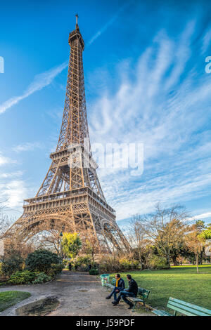 Due uomini seduti su una panchina di fronte alla Torre Eiffel, Parigi, Francia Foto Stock