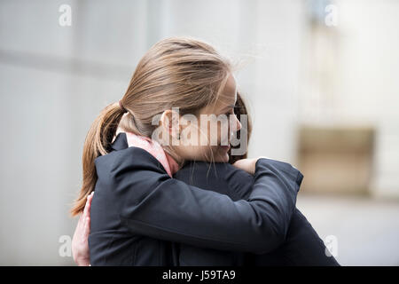 Due lieti imprenditrici che abbraccia ogni altra fuori ufficio. Foto Stock