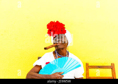 Donna cubana con sigaro in bocca in posa per i turisti a guadagnare denaro per le foto Cuba Havana donna sigaro in posa con ventola Caraibi donna Foto Stock