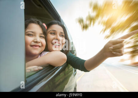 Sorridente madre e figlia a guardare fuori dalla finestra per auto Foto Stock