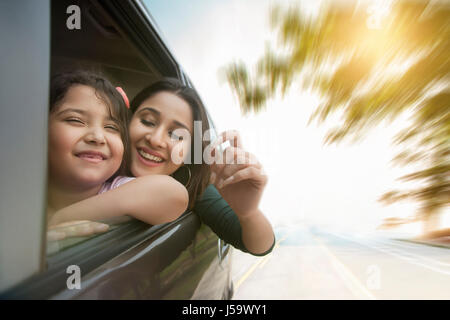 Sorridente madre e figlia a guardare fuori dalla finestra per auto Foto Stock