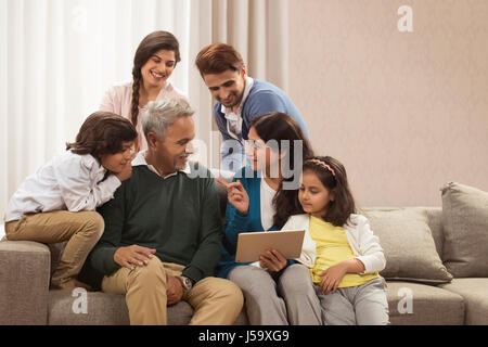 Ritratto felice multi generazione famiglia utilizzando digitale compressa seduto sul divano Foto Stock