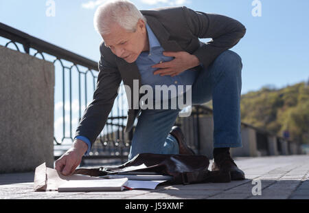 Il vecchio uomo ricerca busta imprevisto nel suo cattivo in strada Foto Stock