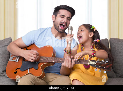 Padre e figlia cantare mentre suonando la chitarra Foto Stock