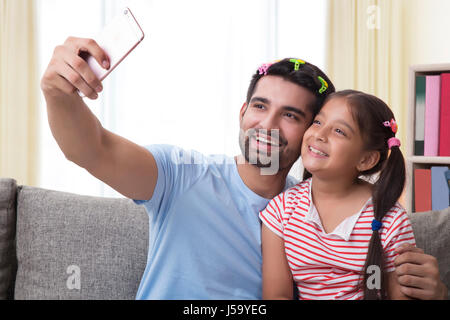 Funny padre indossando le graffe dei capelli e la figlia tenendo selfie Foto Stock