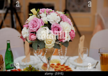 Disposizione di nozze in un bicchiere alto in bianco e i toni di colore rosa. Composta da i garofani e le rose. Decorazioni per matrimoni Foto Stock