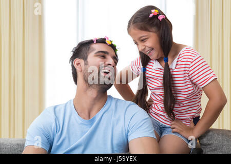 Sorridente funny padre indossando le graffe dei capelli come figlia Foto Stock