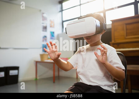 Felice ragazzo che indossa la realtà virtuale simulatore mentre in piedi a casa contro la finestra Foto Stock