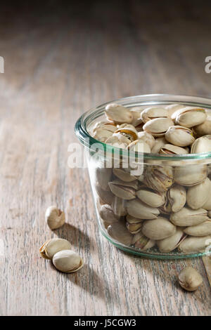 Ciotola di pistacchi di Bronte seduto su una tavola in legno rustico. Foto Stock