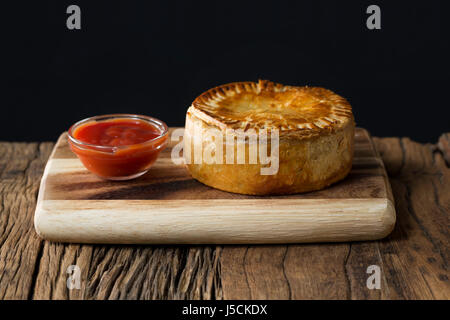 Un britannico tradizionale torta a base di carne seduto su una tavola in legno rustico. Foto Stock