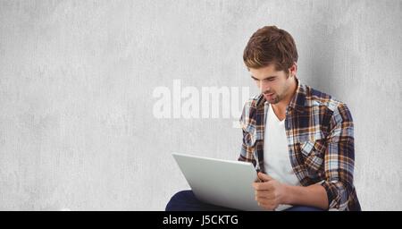 Composito Digitale del giovane uomo utilizzando laptop contro la parete Foto Stock