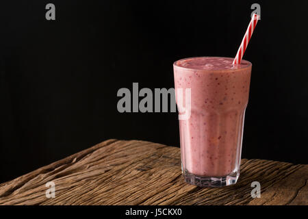 Un bicchiere di fresco frutta berry smoothie, su un rustico sfondo di legno. Foto Stock