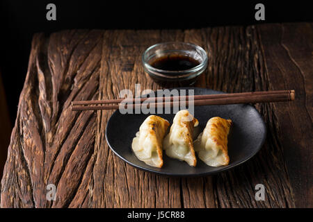 Una piastra di giapponese gnocchi gyoza seduto su una tavola in legno rustico. Foto Stock