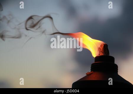 Le fiamme e il fumo aumenta da un illuminato torcia tiki Foto Stock