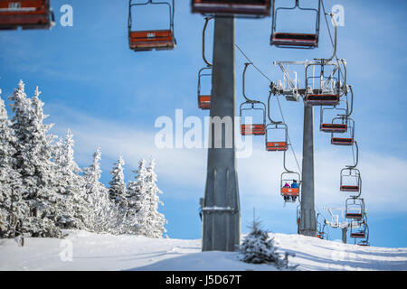 Impianti di risalita con gli sciatori trasportato fino alla collina su una bella e soleggiata giornata invernale Foto Stock