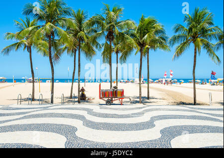 Luminoso vista panoramica della spiaggia di Copacabana con palme accanto alla mitica boardwalk a Rio de Janeiro in Brasile Foto Stock