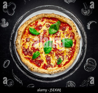 Una gustosa pizza italiana con basilico Foto Stock