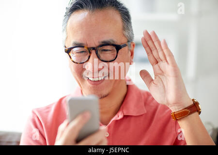 Uomo felice avente chiamata video sullo smartphone a casa Foto Stock