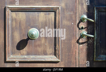 Grande manopola dello sportello la colata di una forte ombra su una porta sbiadito e dotato di due maniglie dello sportello. Foto Stock