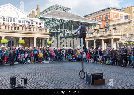 I turisti a guardare un animatore di strada nel mercato di Covent Garden di Londra Foto Stock