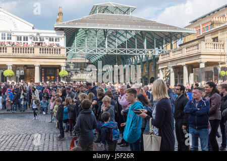 I turisti a guardare un animatore di strada nel mercato di Covent Garden di Londra Foto Stock