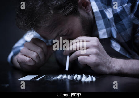 Esperto junky Sniffing linee di eroina in luogo oscuro Foto Stock
