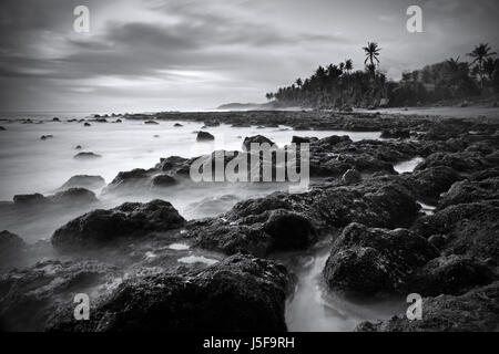 Bella in bianco e nero fine art foto di una Bali beach scena. Drammatica lunga esposizione tecnica che utilizza la modalità monocromatica per creare atmosfera durante il tramonto Foto Stock