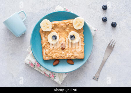 Burro di arachidi toast per bambini in forma di divertente carino gufo su una piastra di blu. Vista superiore Foto Stock