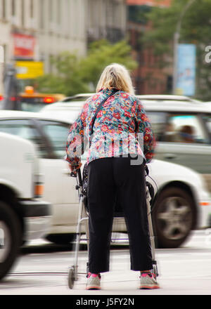 Un fragile donne anziane tentando di attraversare una affollata e trafficata strada pericolose Foto Stock