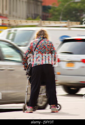 Un fragile donne anziane tentando di attraversare una affollata e trafficata strada pericolose Foto Stock