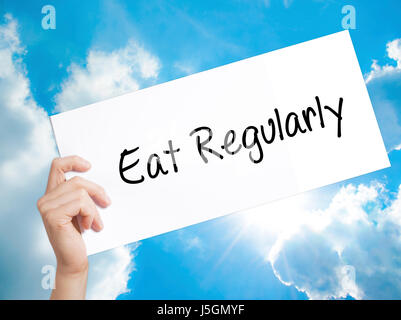 Mangia regolarmente segno su carta bianca. Man mano che tiene la carta con testo. Isolato su sfondo cielo. Il concetto di business. Stock Photo Foto Stock